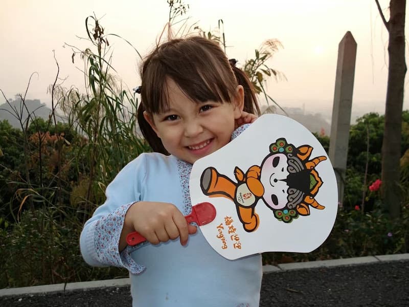 Ailyn as a little girl hiking, holding a fan with the Beijing Olympic mascots